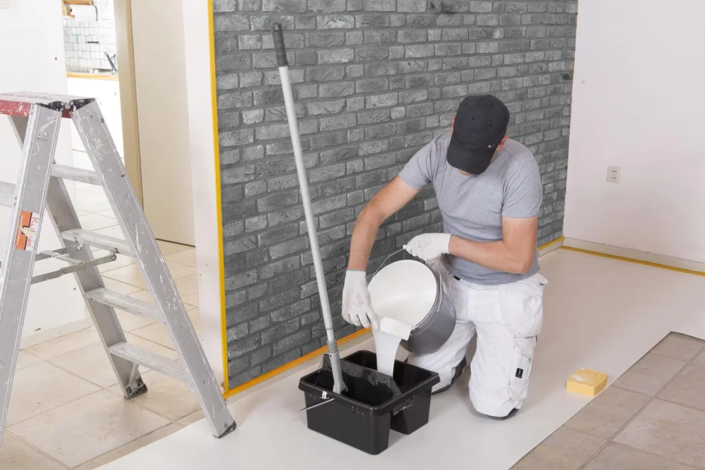 Malarz nalewa farbę do wiadra Go!Paint Roll & Go XL podczas remontu